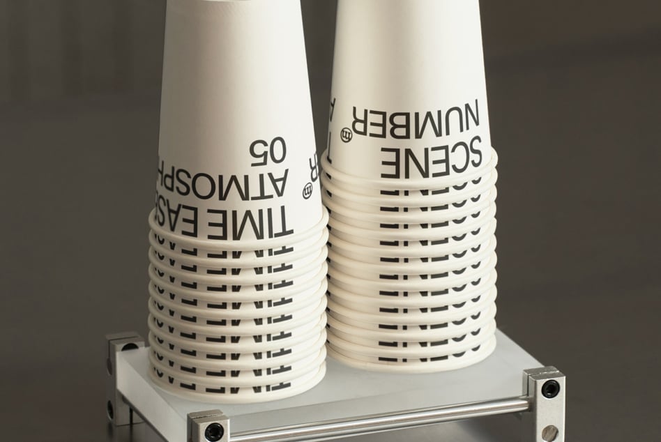 Cream colored stacked cups displaying text branding on white platform with metal base