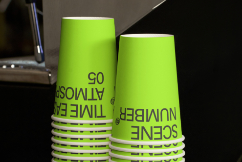Two lime green cups in close-up showing band detail, sitting on dark surface with lighting
