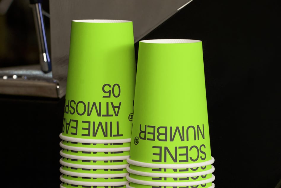 Two lime green cups in close-up showing band detail, sitting on dark surface with lighting