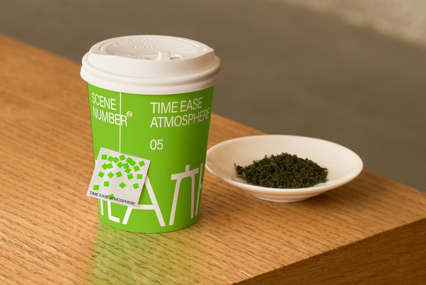 Bright green coffee cup with white lid, teabag, dry tea leaves in white bowl