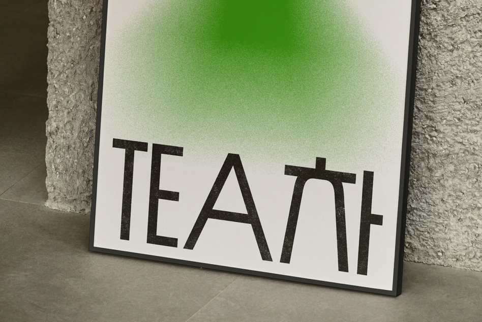 White poster with green gradient displaying TEAL text leaning against concrete wall