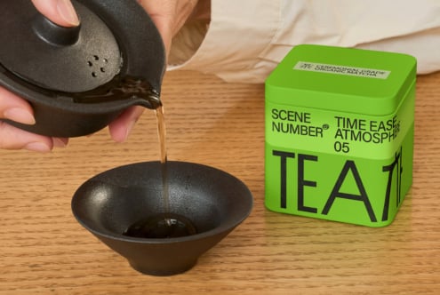 Pouring from black teapot into ceramic bowl with green canister