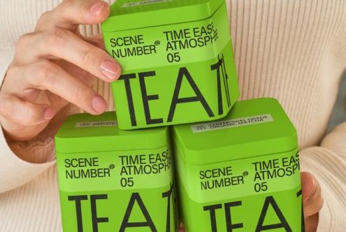 Stacked neon green tea canisters being held up by one hand