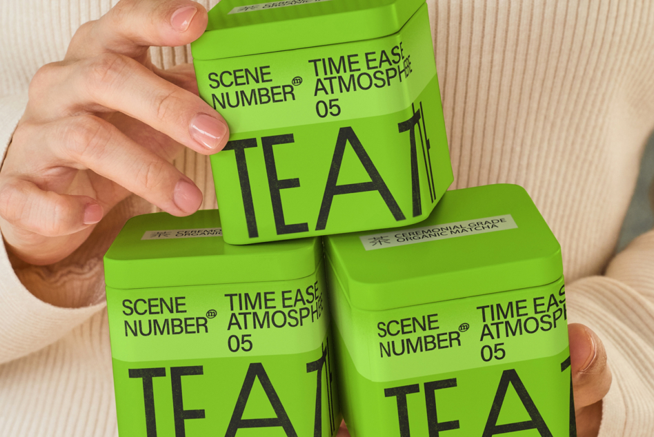 Stacked neon green tea canisters being held up by one hand