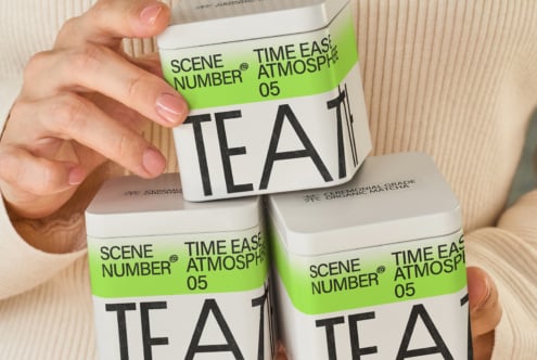 Hand holding lime green tea canister stacked with two white boxes