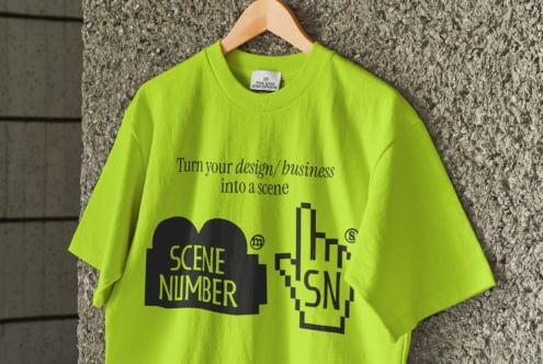 Bright lime tee with Scene Number branding displayed on wooden hanger