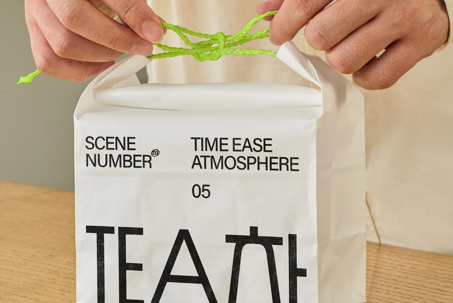 Hands holding open white paper bag with Scene Number tea packaging inside