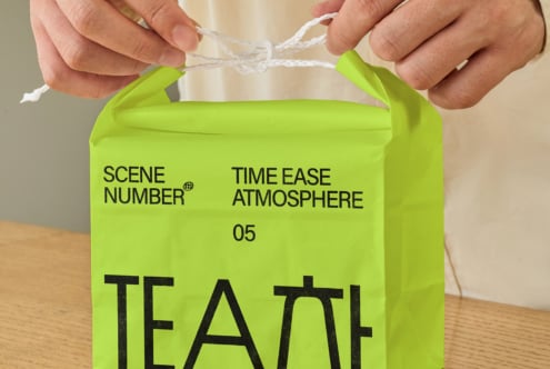 Hands holding neon green paper bag with twine handles showing printed branding