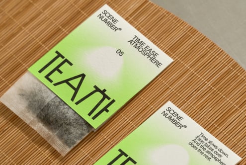 Two folded postcards with lime green upper sections showing Tea Time Ease Atmosphere branding, wood grain background