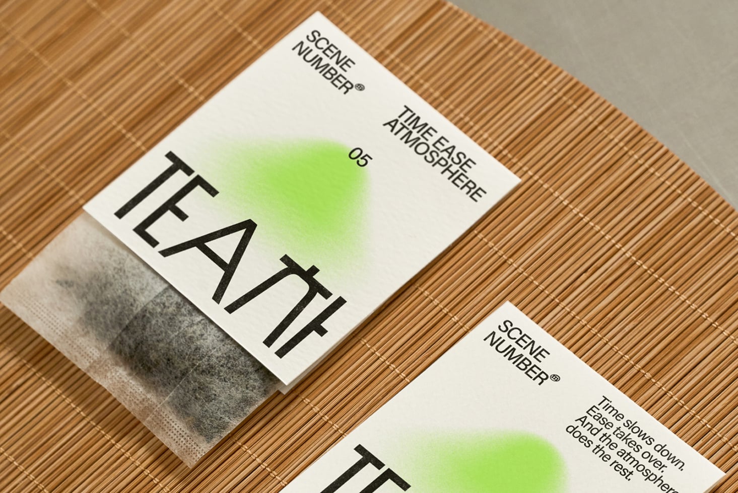Angled overhead of two tea packages on rattan with fabric texture details visible