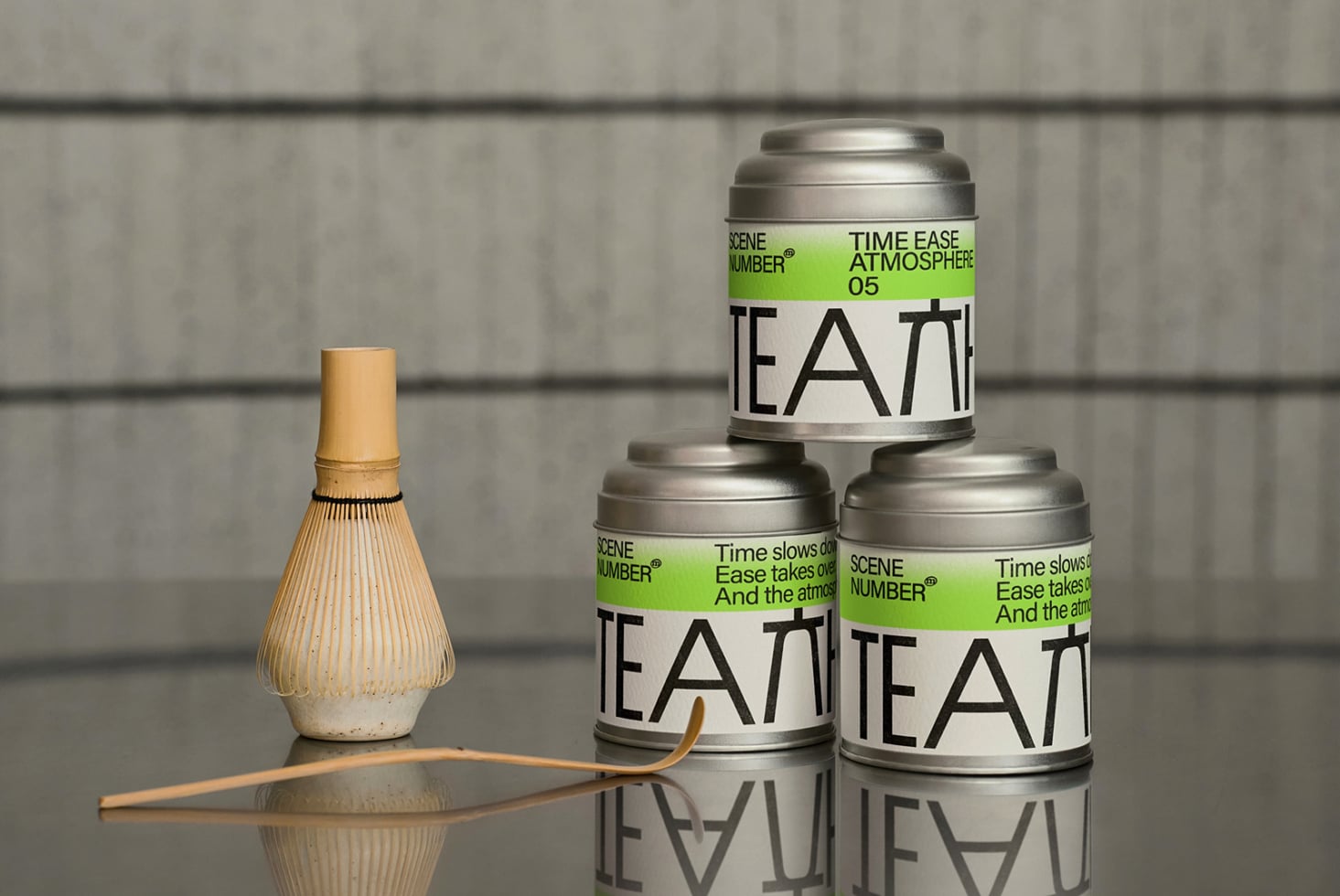 Stacked metal tea cans with matcha whisk, concrete background, editable labels