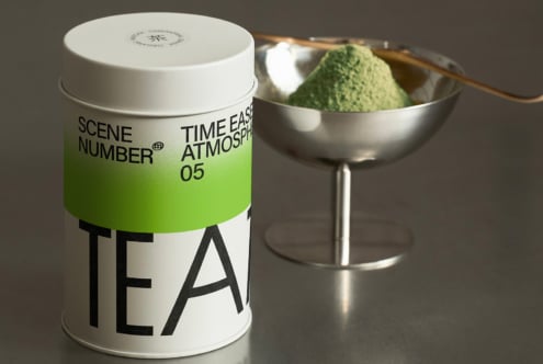 White tea tin with green band, matcha in silver bowl, traditional bamboo whisk setup