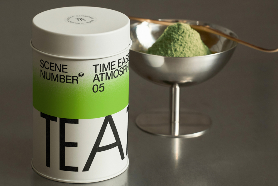 White tea tin with green band, matcha in silver bowl, traditional bamboo whisk setup