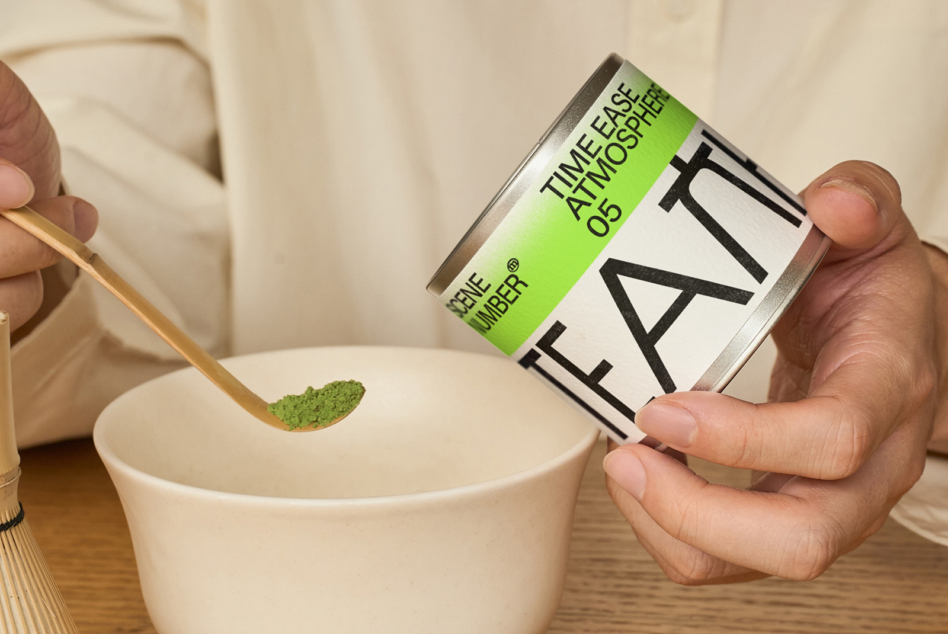 Hand pouring green matcha powder from branded tin into ceramic bowl