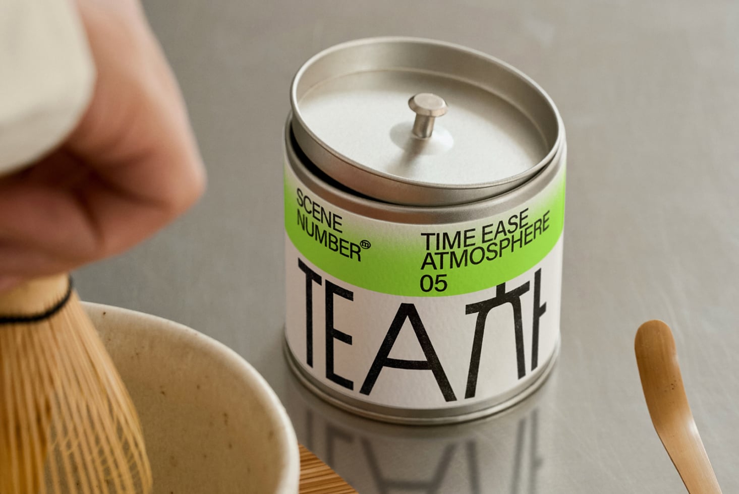 Metallic tin candle with bright lime label for tea product, wooden spoon nearby