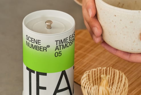 Two-tone green tea canister with white ceramic lid near matcha tools