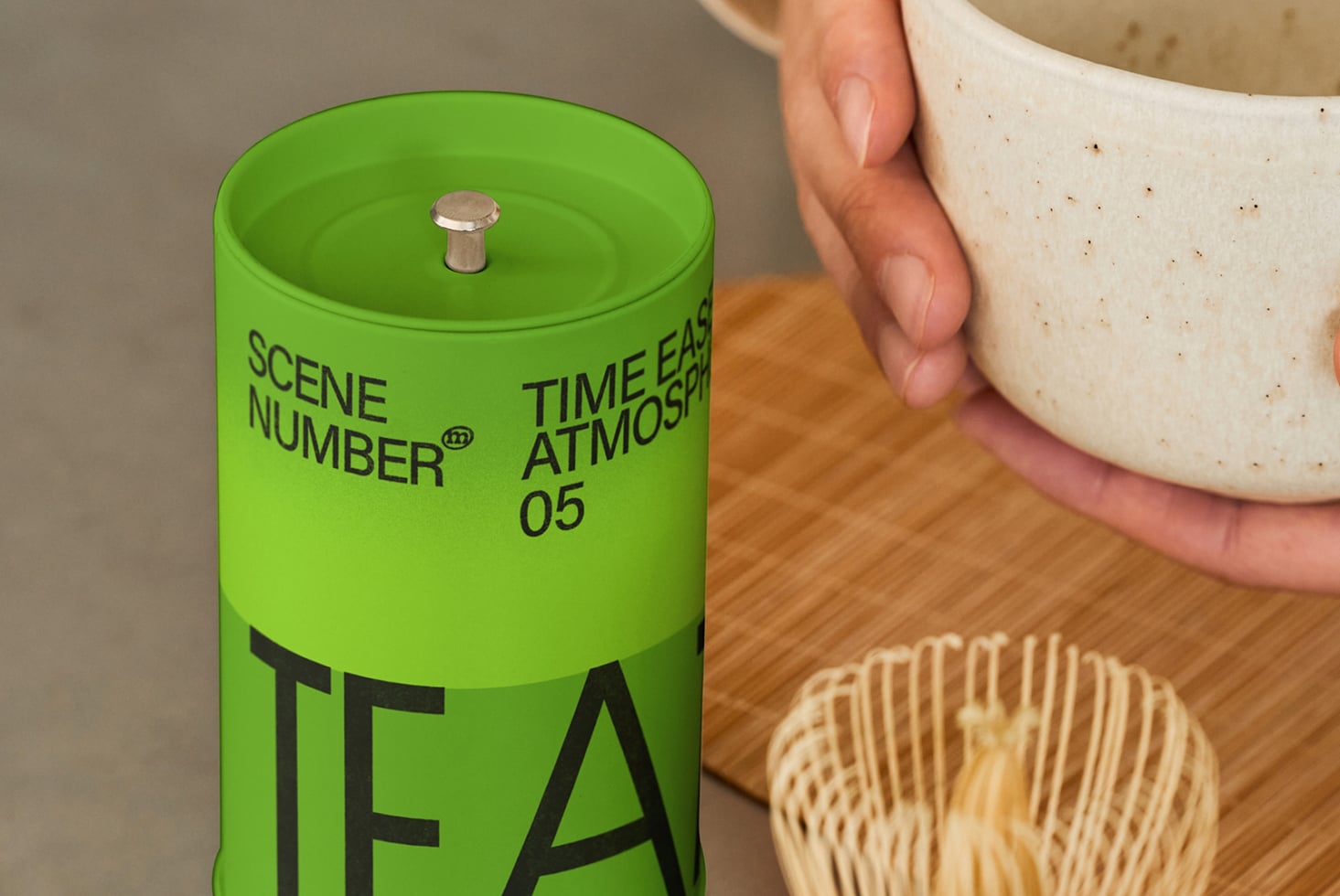 Green cylindrical tea canister with metal top on wooden table