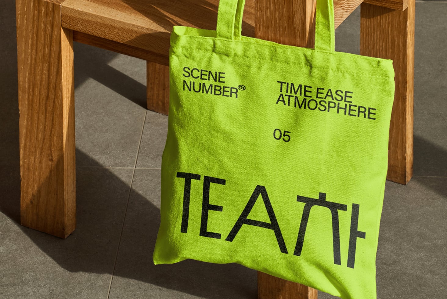 Lime green tote bag hanging on wooden chair with TEA text printed front