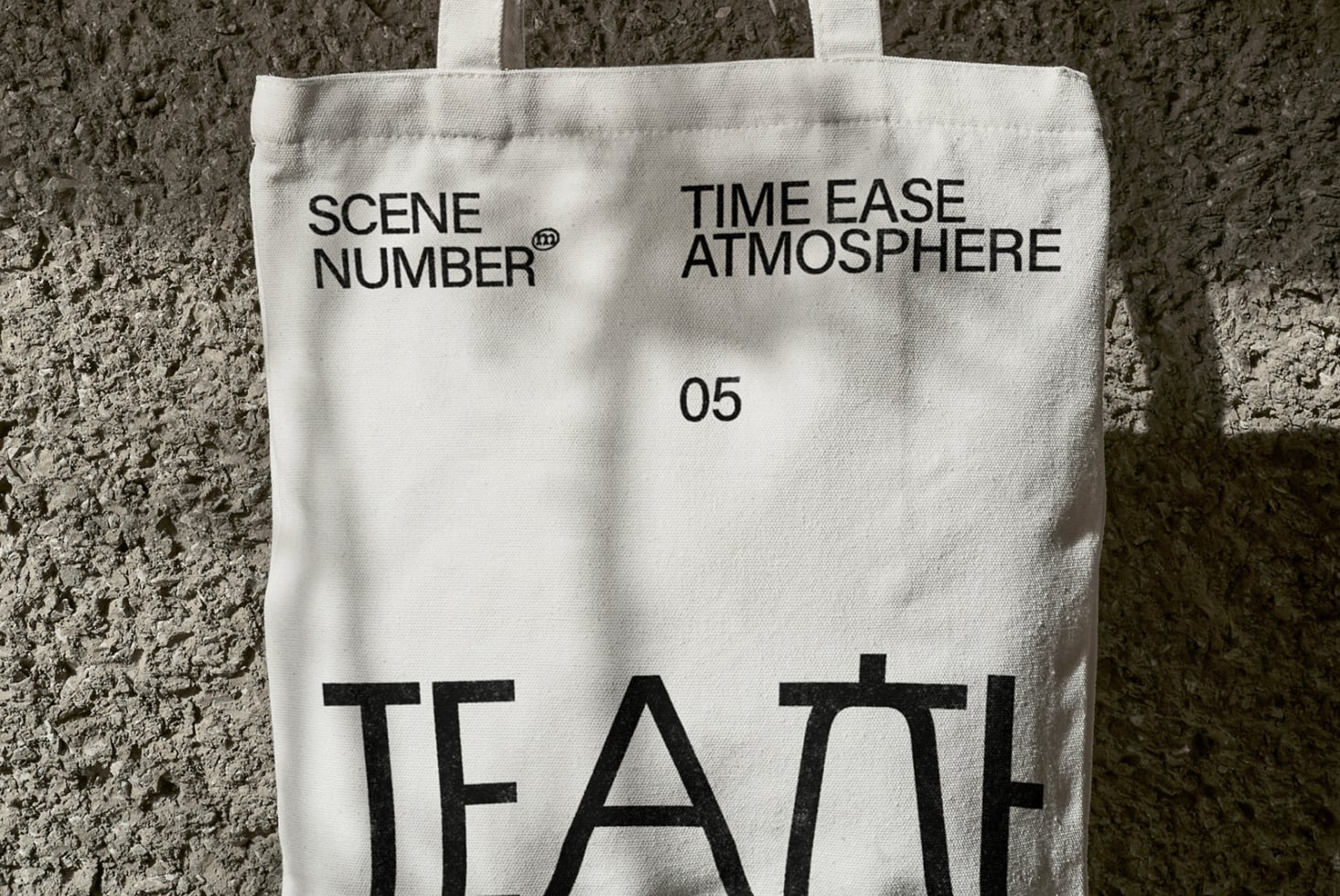 Off white canvas tote with black lettering against rough gray brick