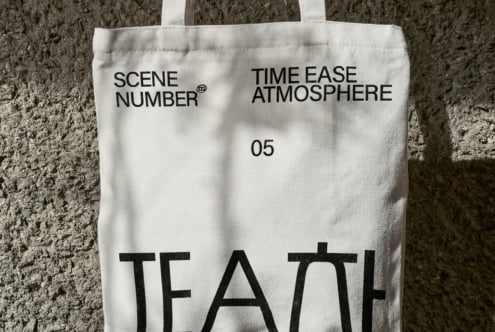 Off white canvas tote with black lettering against rough gray brick