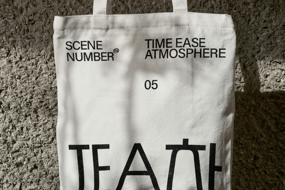 Off white canvas tote with black lettering against rough gray brick