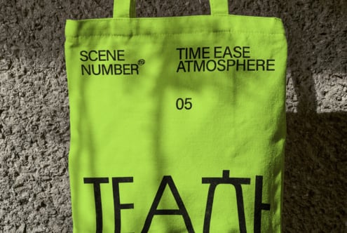 Neon lime tote bag against concrete wall with black typography