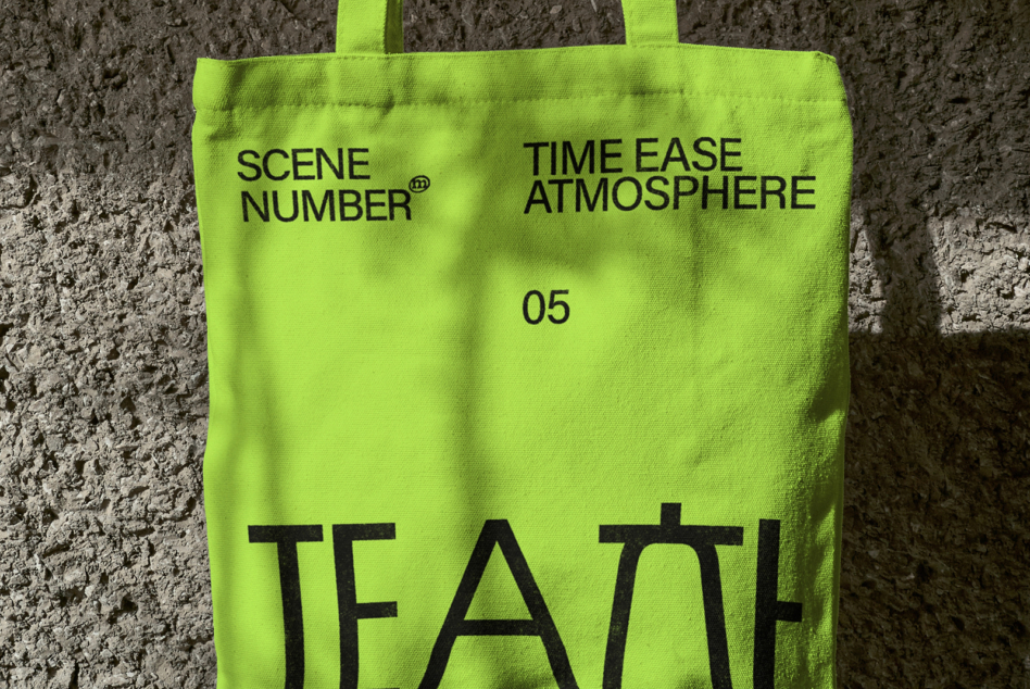Neon lime tote bag against concrete wall with black typography