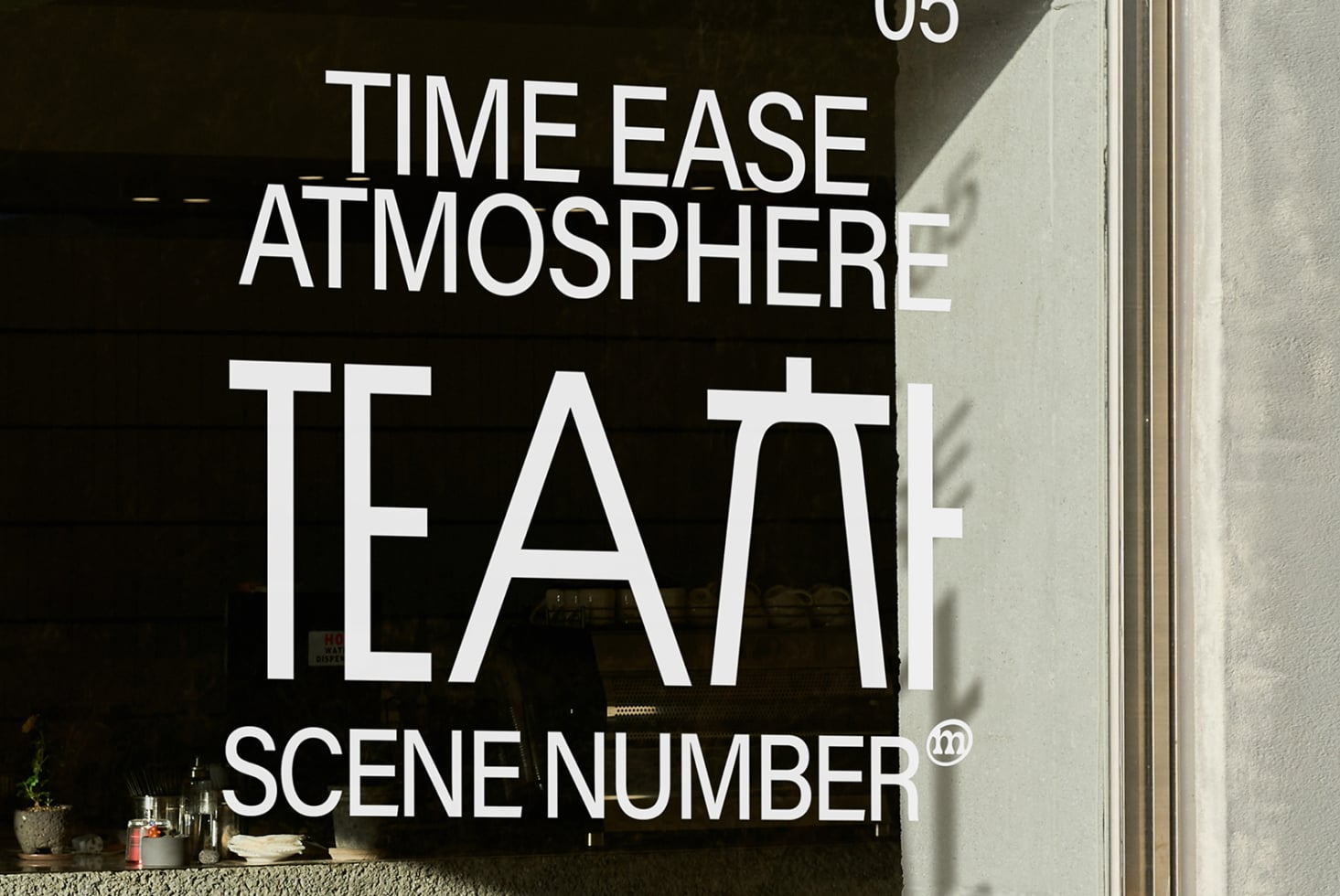 White neon text on dark storefront window displaying tea scene branding