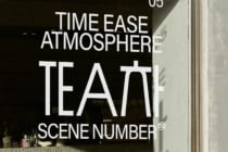 White neon text on dark storefront window displaying tea scene branding