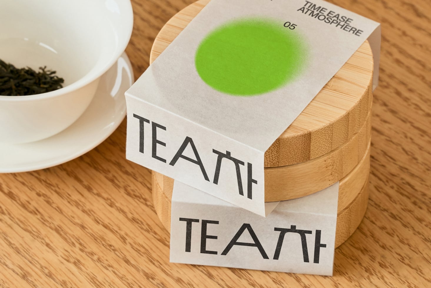 White tea box with green gradient circle on wooden container by cup
