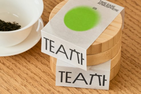White tea box with green gradient circle on wooden container by cup
