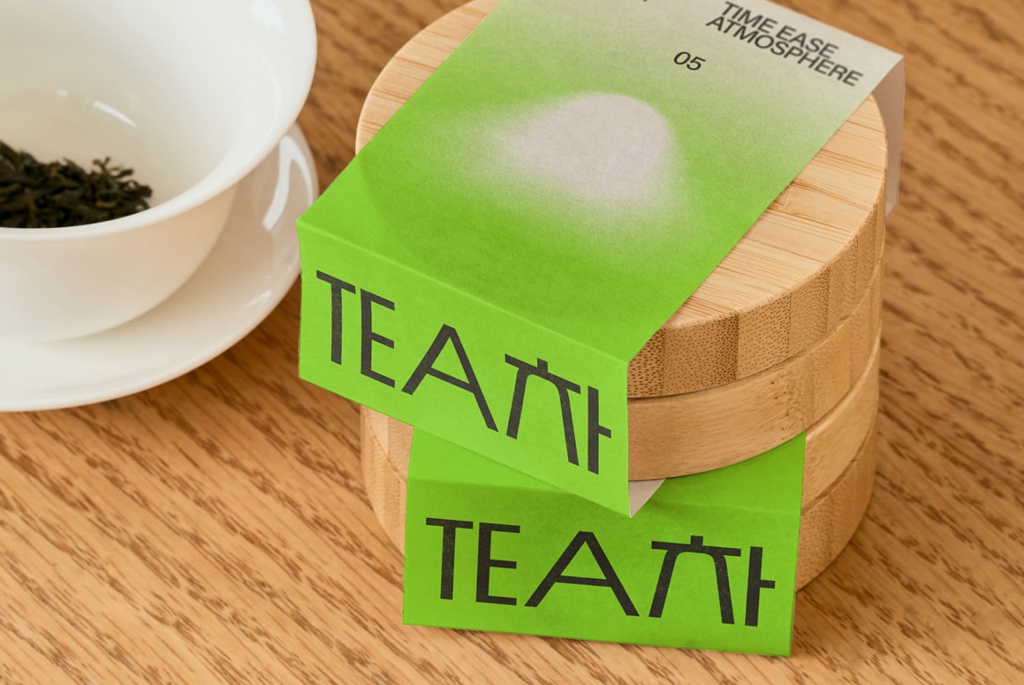 Bright green tea box with white label bands sitting on wooden tea caddy