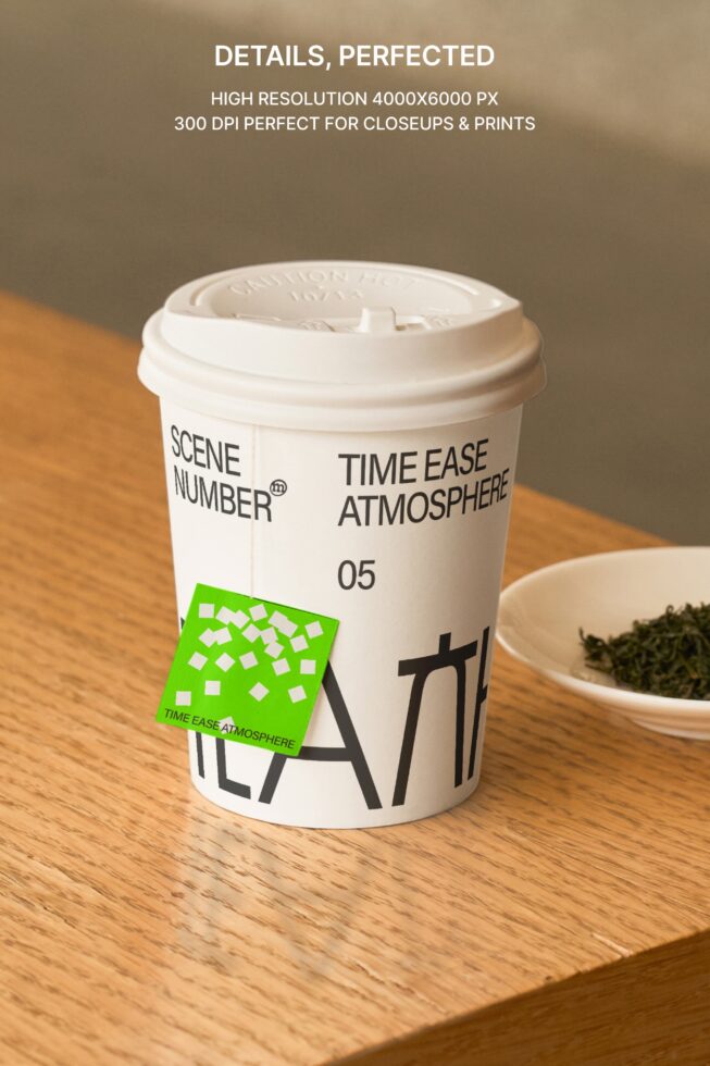 White coffee cup with green tea bag tag on wooden table next to ceramic dish