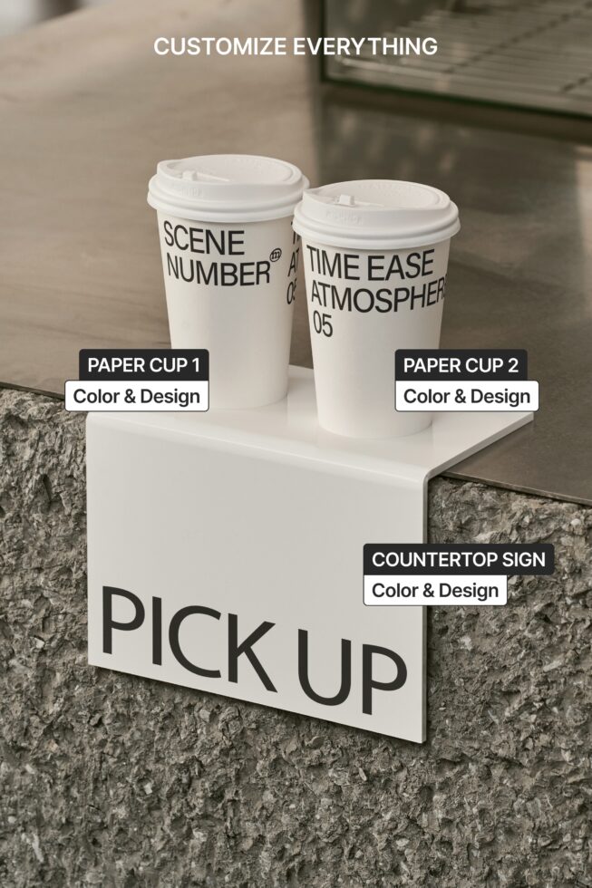 Two white paper cups with neon green sign on countertop against brick