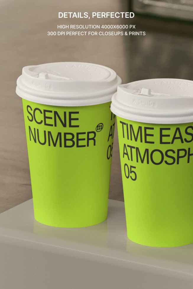 Close-up of two lime green paper cups with white lids on concrete surface