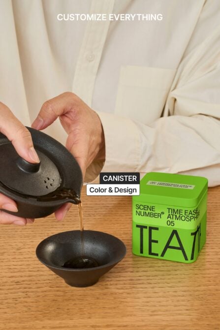 Pouring liquid from black vessel into bowl next to green tea box
