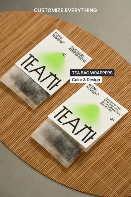 Two tea bag wrappers arranged on woven placemat with green gradient design