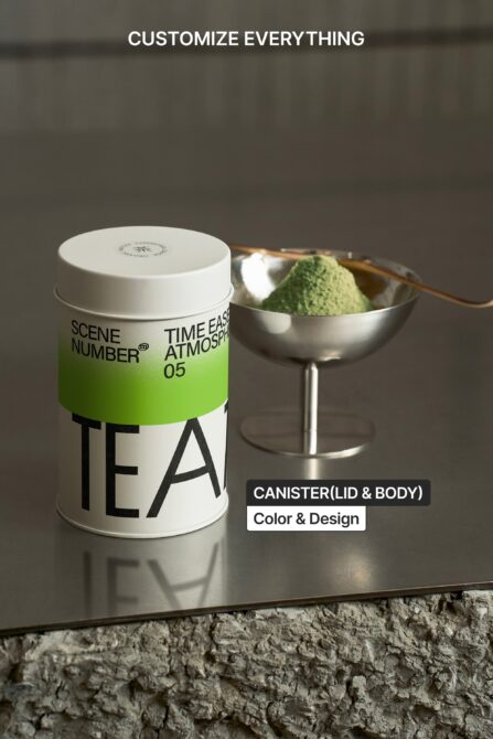 Single tea canister next to silver bowl filled with matcha powder, wooden utensil visible