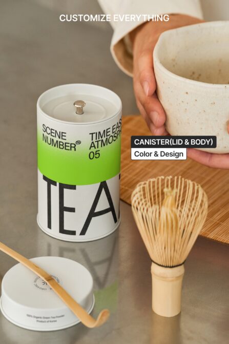 Green tea canister with lid next to ceramic bowl on wooden surface