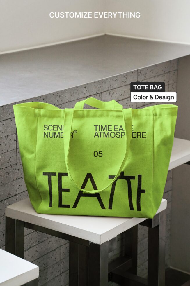 Bright lime tote bag with black TEA text, sitting on white platform with concrete wall