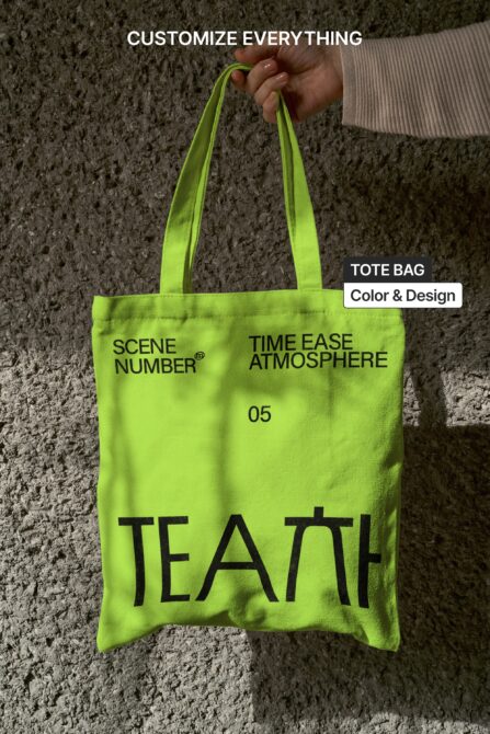 Neon yellow tote bag being held displaying bold black printed text design