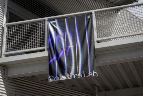 Dark fabric banner with neon blue pink streaks hanging on metal railing