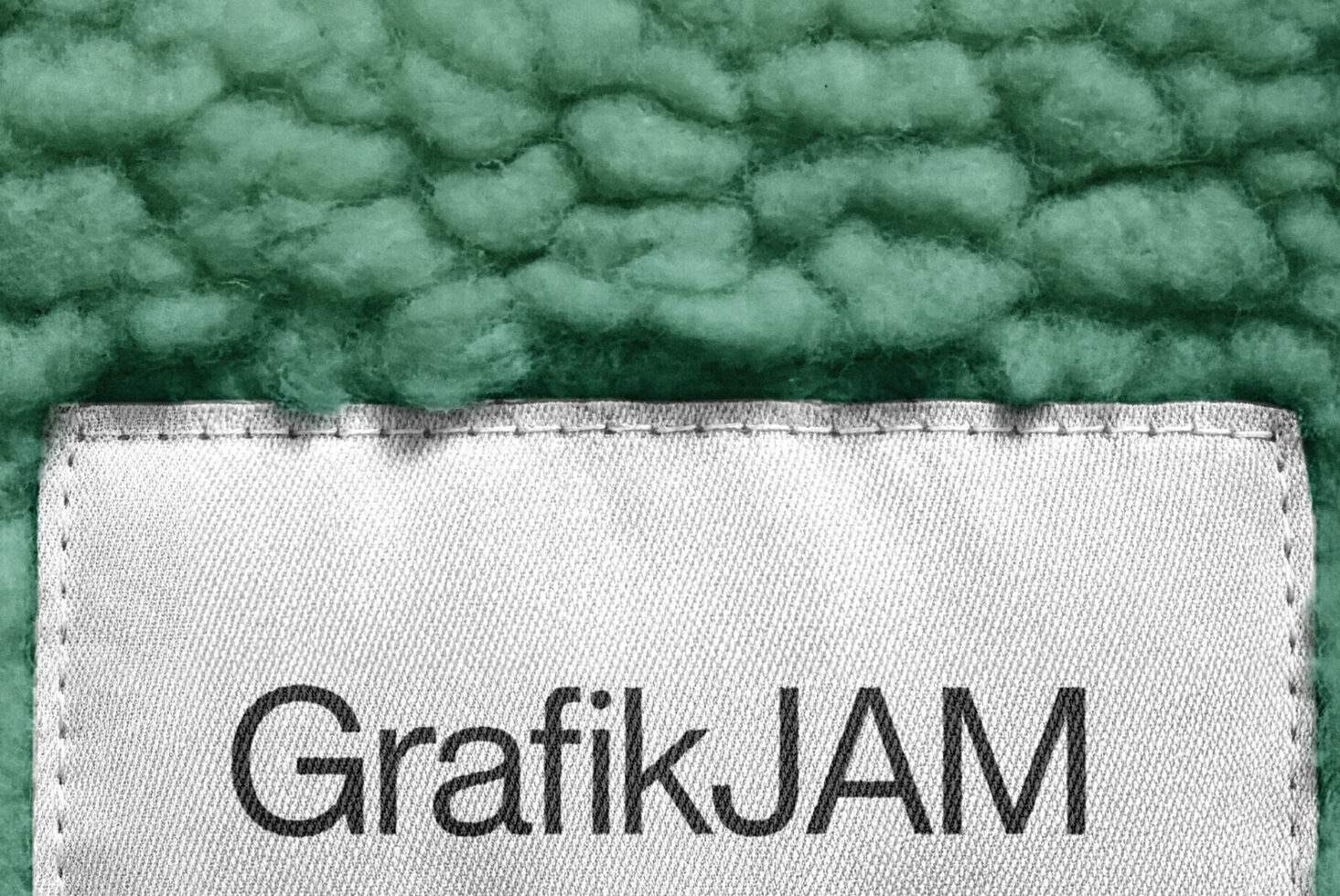 GrafikJAM text on cream fabric label sewn onto bumpy green textile