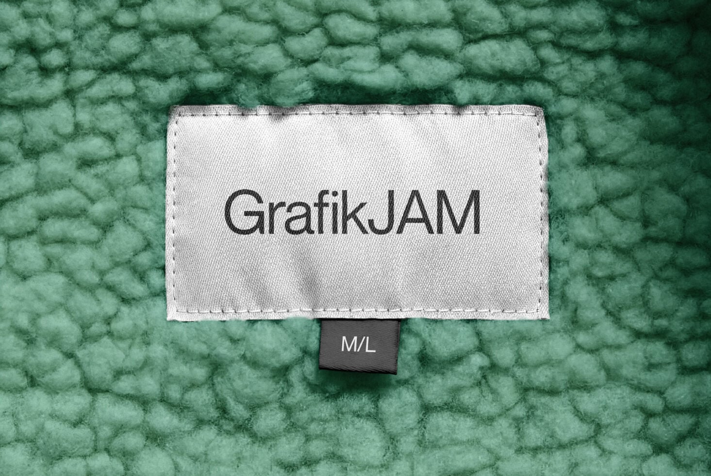GrafikJAM text on white label attached to textured green fabric, M/L tag shown
