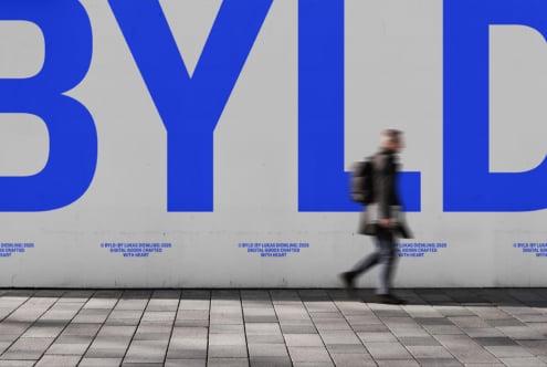 Blurred runner moving past large blue BYLD typography on wall