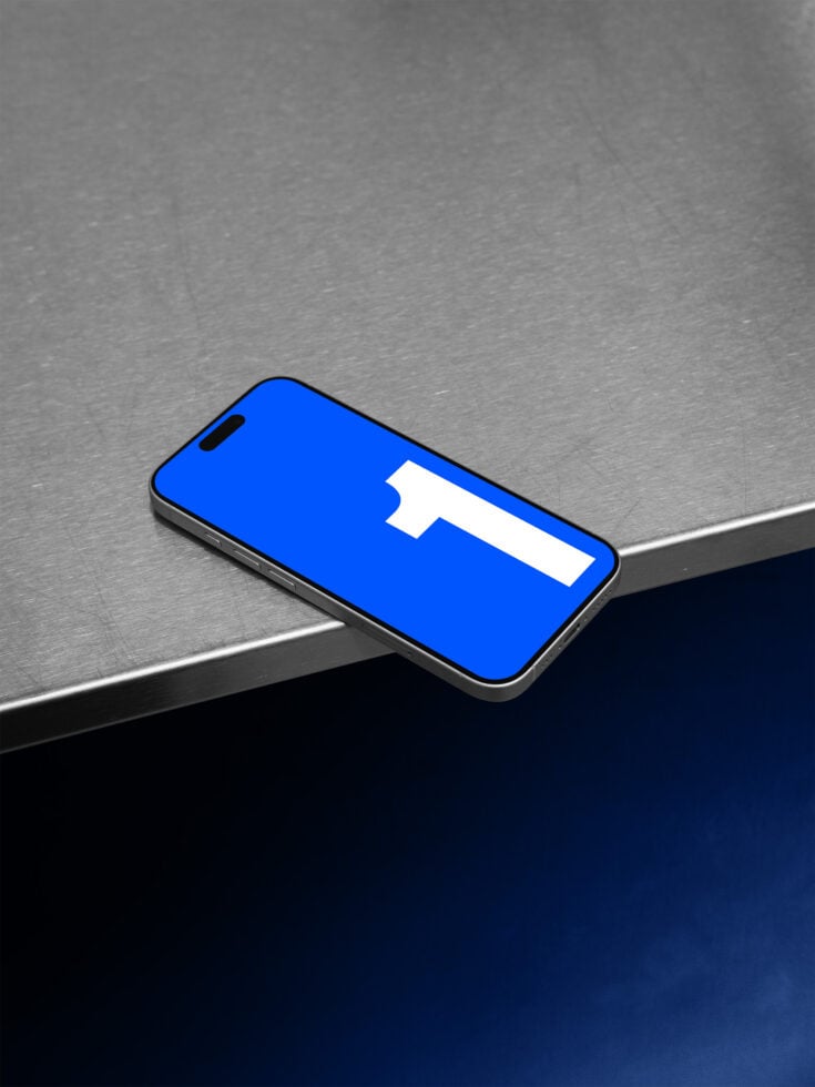 iPhone displaying Facebook app with blue interface on industrial surface