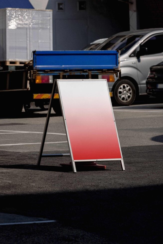 A-frame sign on parking lot showing pink to white gradient mockup surface
