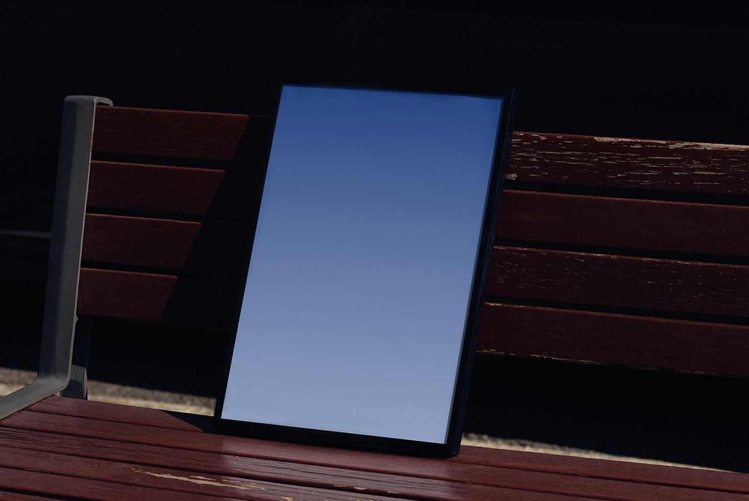 Blank poster mockup on wooden bench at night showing clean blue display surface