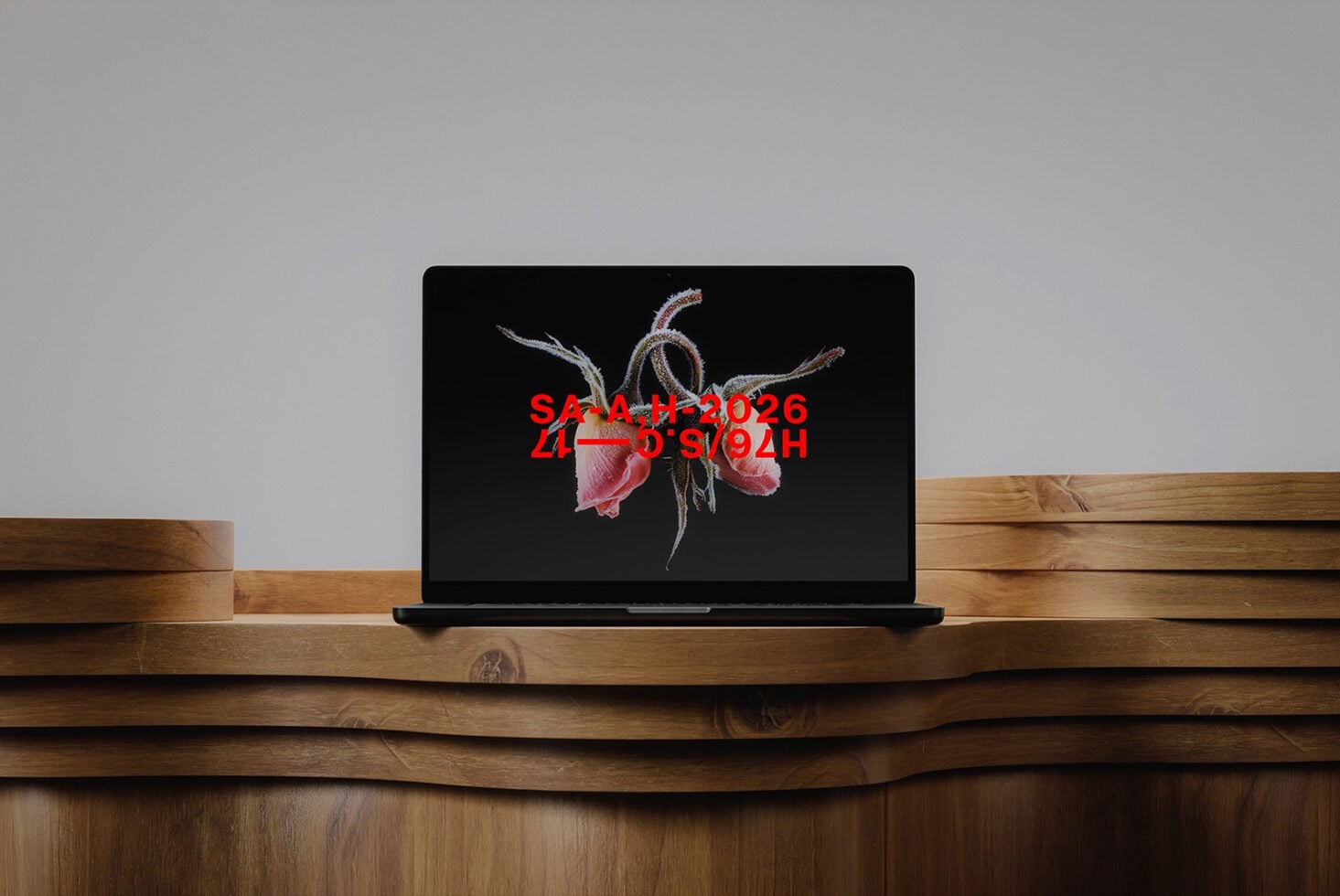 Laptop mockup on curved wood shelf displaying botanical artwork with red text