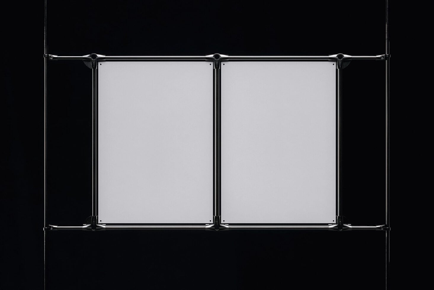 Industrial metal clamps suspending dual blank posters on black background